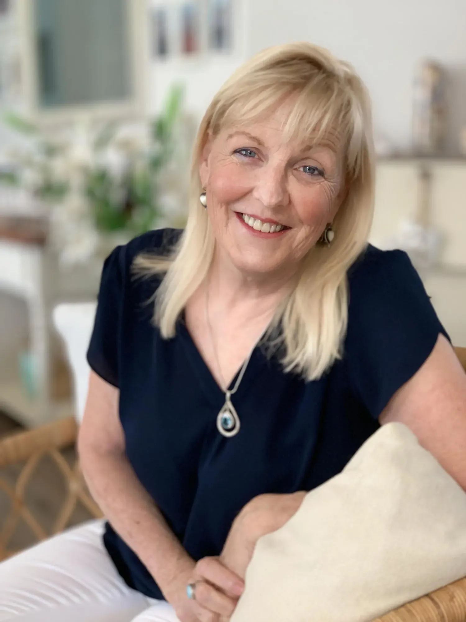 Kim Jewell, smiling, seated in a bright living room.